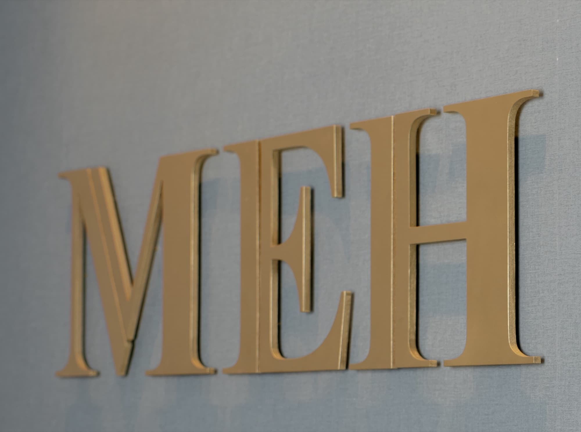 The gold MEH letters on the office wall